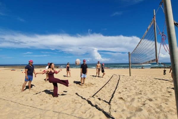 Corporate participant spiking a ball over the net during a beach volleyball game at a Pinnacle Team Events Mini Beach Olympics team building event