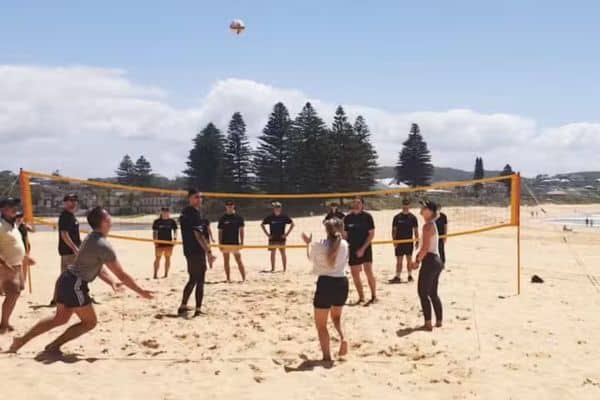 Corporate team playing beach volleyball during a Mini Beach Olympics outdoor team building event with Pinnacle Team Events