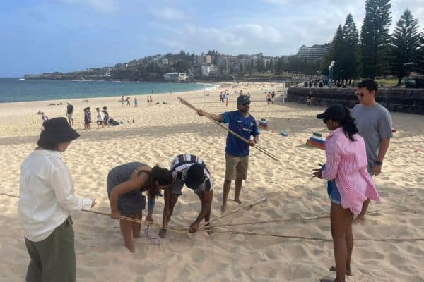 Corporate team members building a tower challenge on the beach during a Mini Beach Olympics outdoor team building event with Pinnacle Team Events