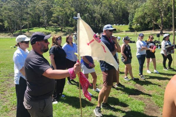 Corporate team member holding a hand-painted team flag on grass during a Mini Olympics outdoor team building event with Pinnacle Team Events