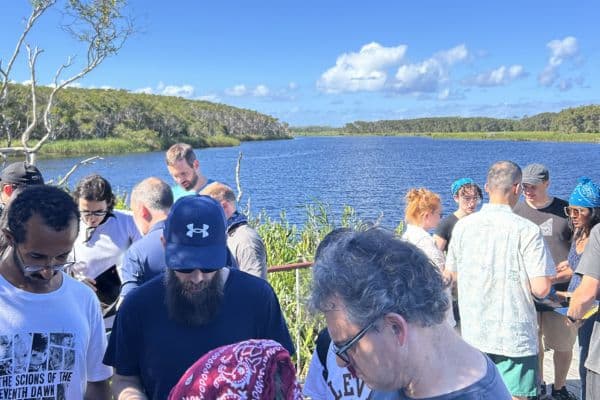 Large group of corporate participants working through a challenge beside a scenic lake during a Ransom outdoor team building event with Pinnacle Team Events