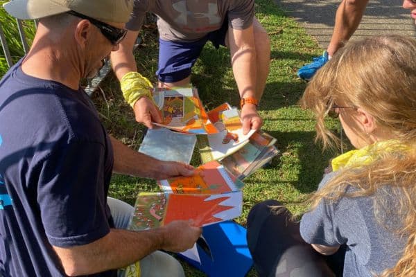 Corporate team working together to solve an outdoor card puzzle on the grass during a Ransom team building event with Pinnacle Team Event