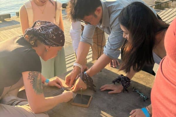 Corporate team members working closely together to solve a hands-on puzzle at a waterfront location during a Ransom team building event with Pinnacle Team Events