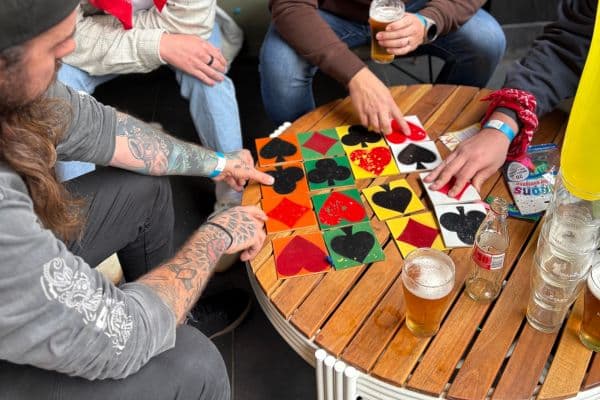 Participants solving a playing card suit tile puzzle at a pub table during The Scramble