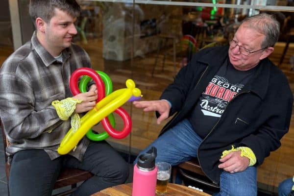 Two Scramble participants with a colourful balloon animal creation at an outdoor venue