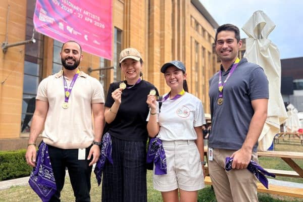 Four Scramble participants proudly displaying their gold medals outside a heritage building