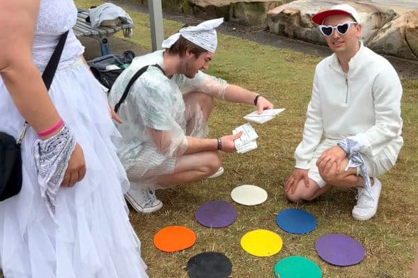 Two participants examining coloured disc puzzle pieces on grass during a Scramble challenge