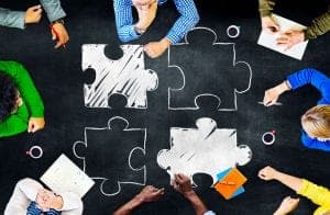 Team sitting around table solving a jigsaw puzzle