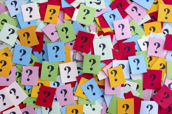 Too Many Questions. Pile of colorful paper notes with question marks. Closeup.
