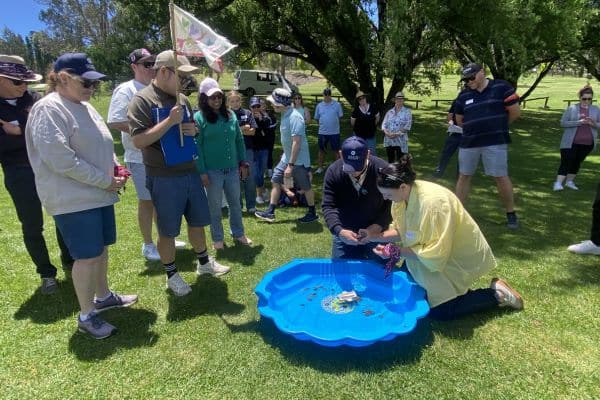 Viatris corporate team huddled together solving a clue on the ground during a Treasure Hunt outdoor team building event with Pinnacle Team Events