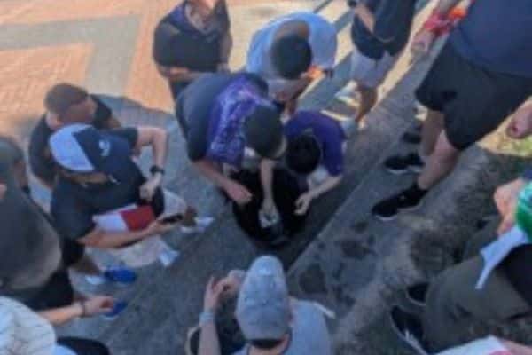 Corporate team sorting clue cards on outdoor steps near a stadium during a Treasure Hunt team building event with Pinnacle Team Events