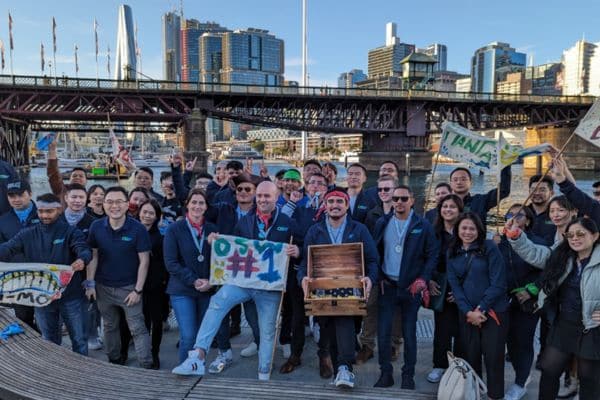 Corporate team posing with a treasure chest and winner medals on a waterfront dock at the end of a Pinnacle Team Events Treasure Hunt