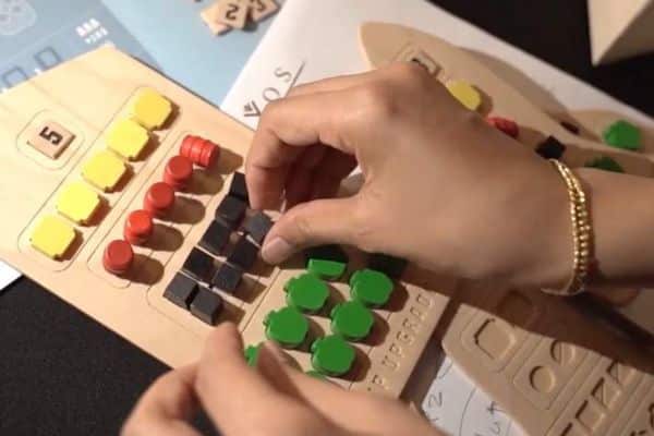 Clos eup of hand moving coloured tiles on wooden board