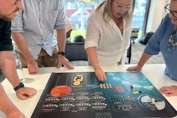 Four people standing around table wokring on Before Mars team-building activity