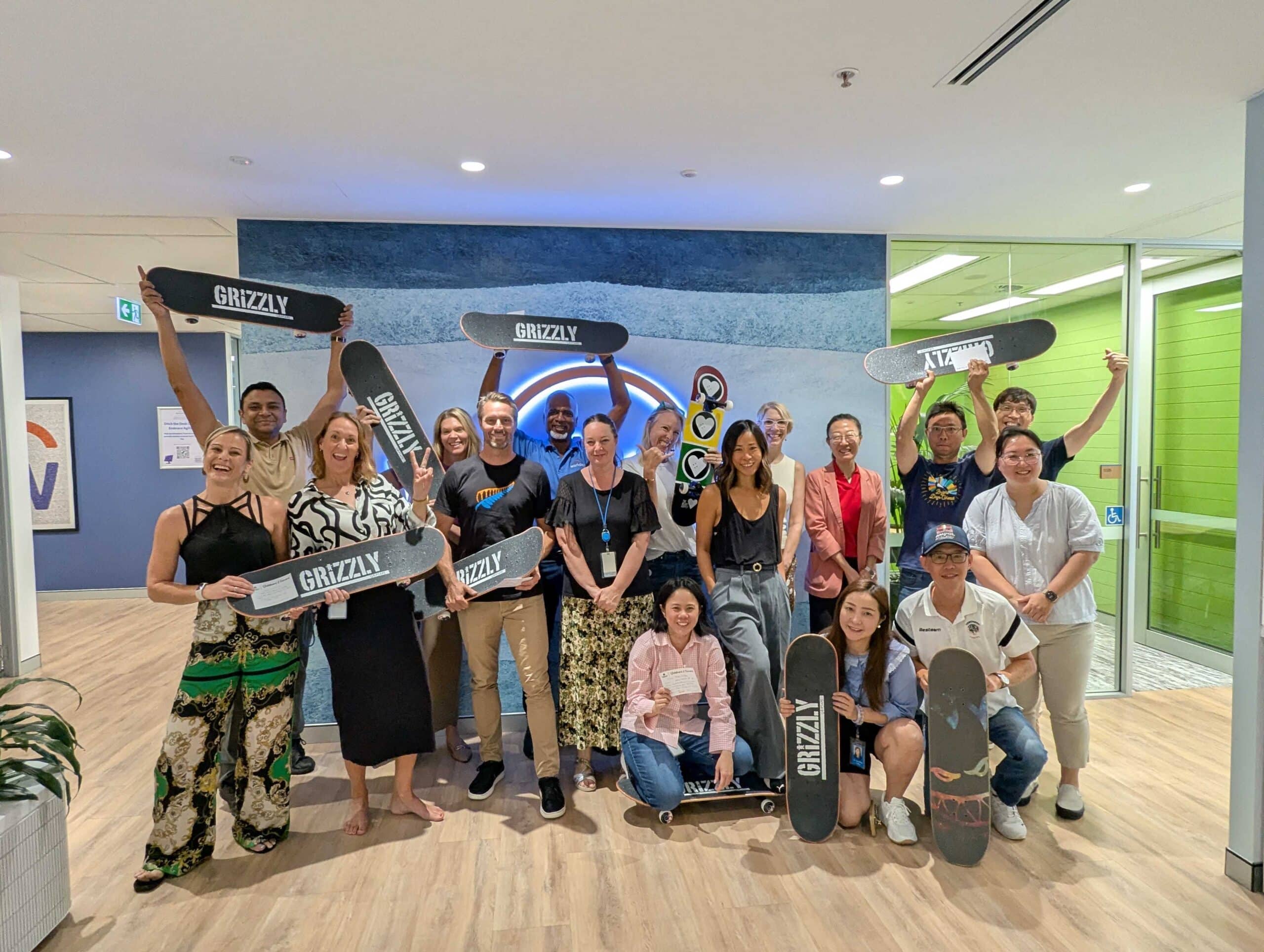 Team holding up skateboards after participating in skateboard it forward event