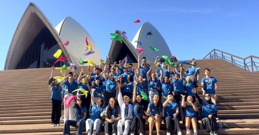 Group of people celebrating and throwing colourful bandanas in the air on the steps of the Sydney Opera House