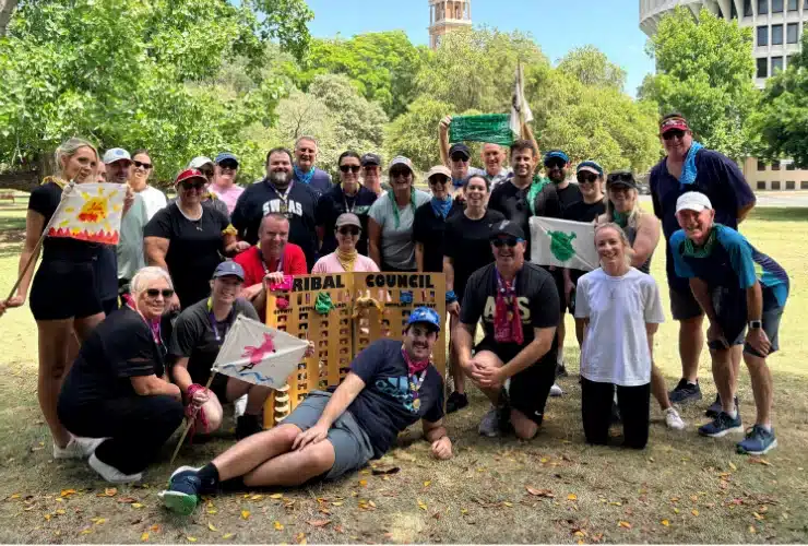 Group of people holding hand painted flags standing around Sruvivor stand