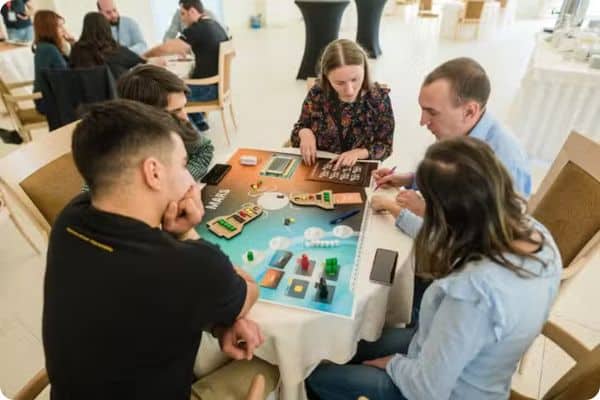 Team development workshop in action. Six people sitting around table playing before mars