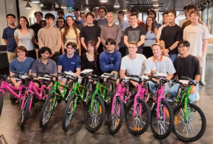 Happy team standing behind bikes they built